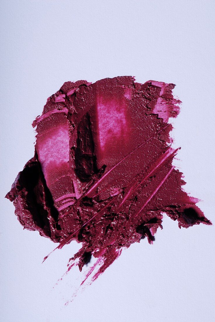 Dark pink lipstick smeared on a white surface