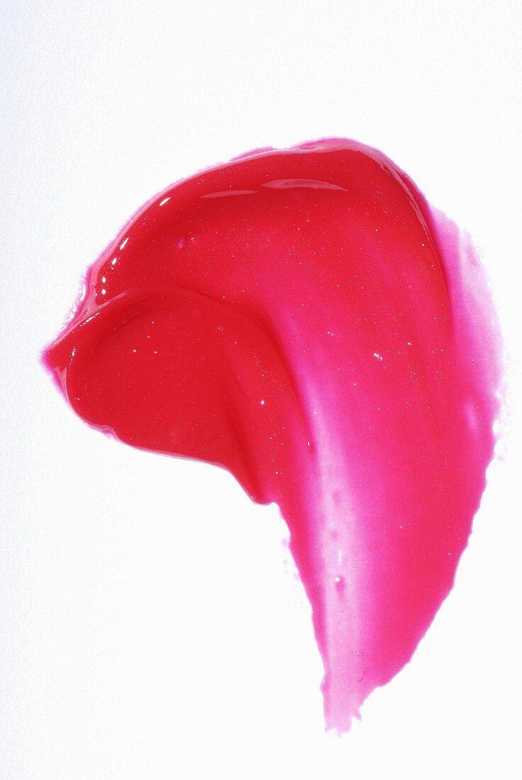 Red lip gloss smeared on a white surface