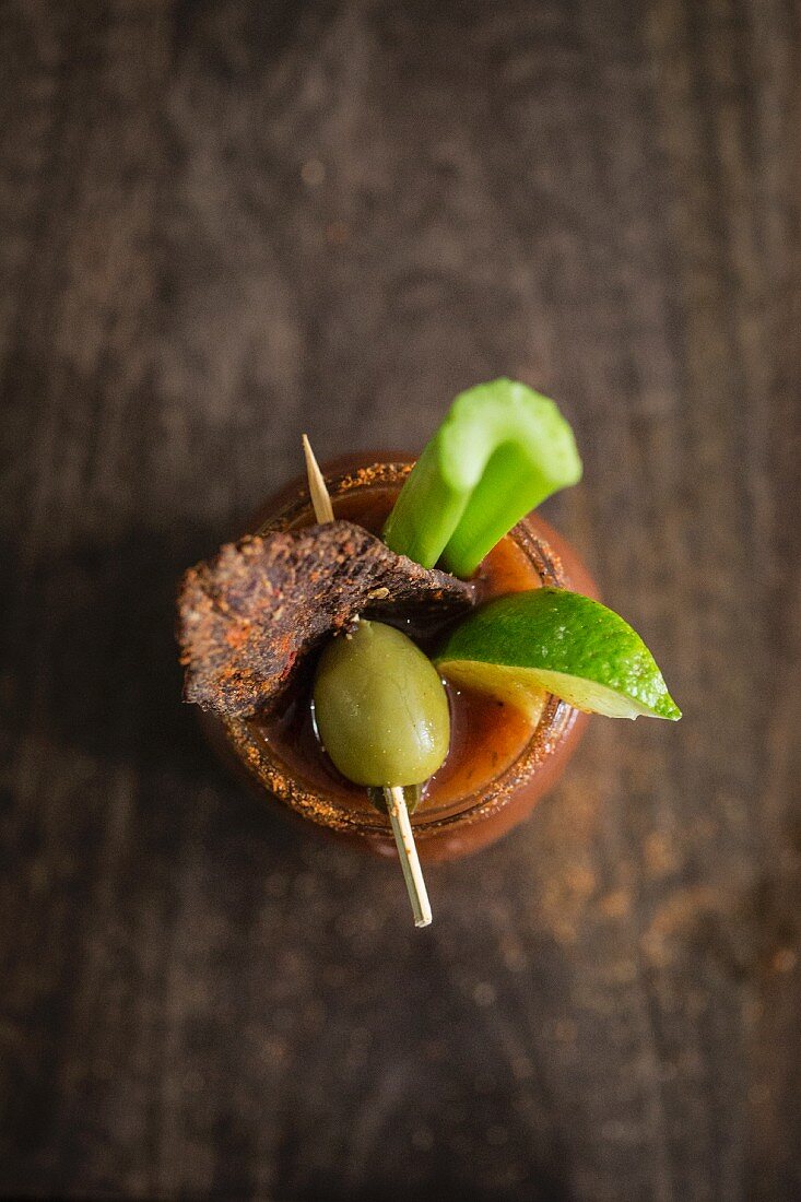 A Bloody Mary with beef jerky, an olive, lime and a stick of celery