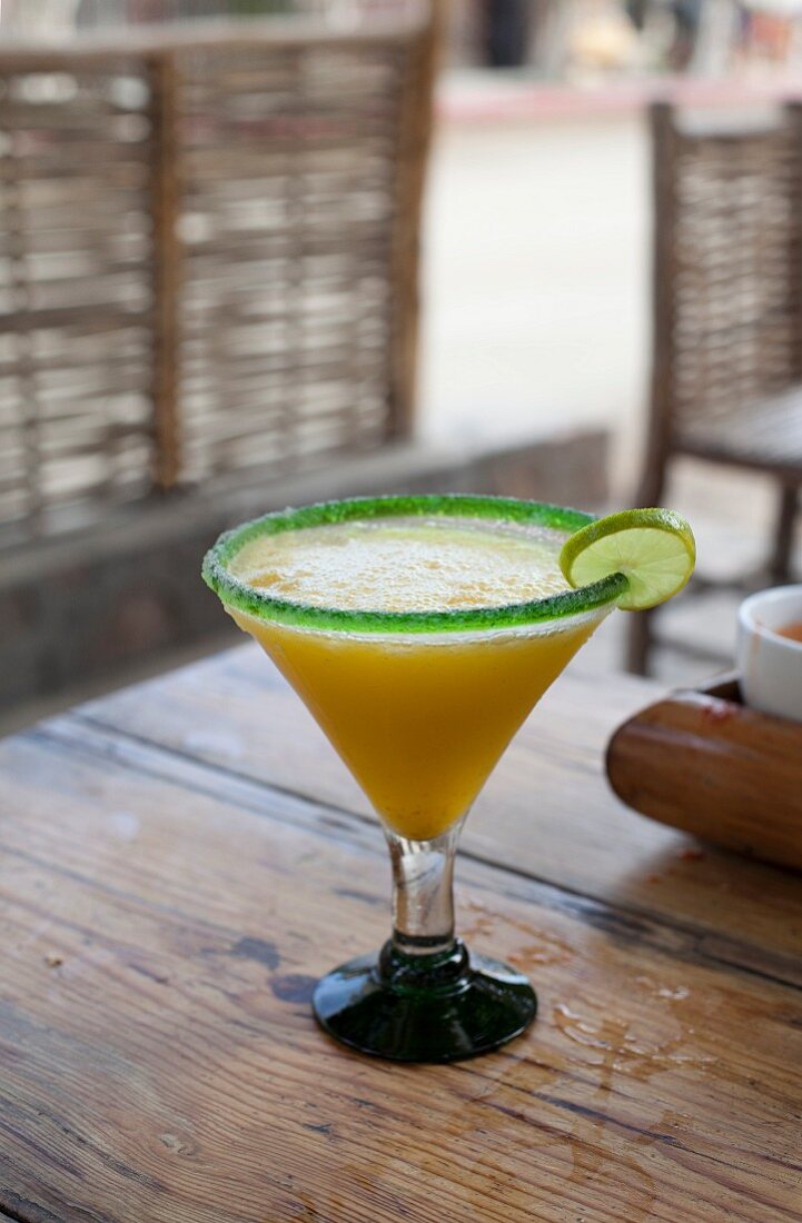 A cocktail with a sugared rim and a lime slice in a street cafe