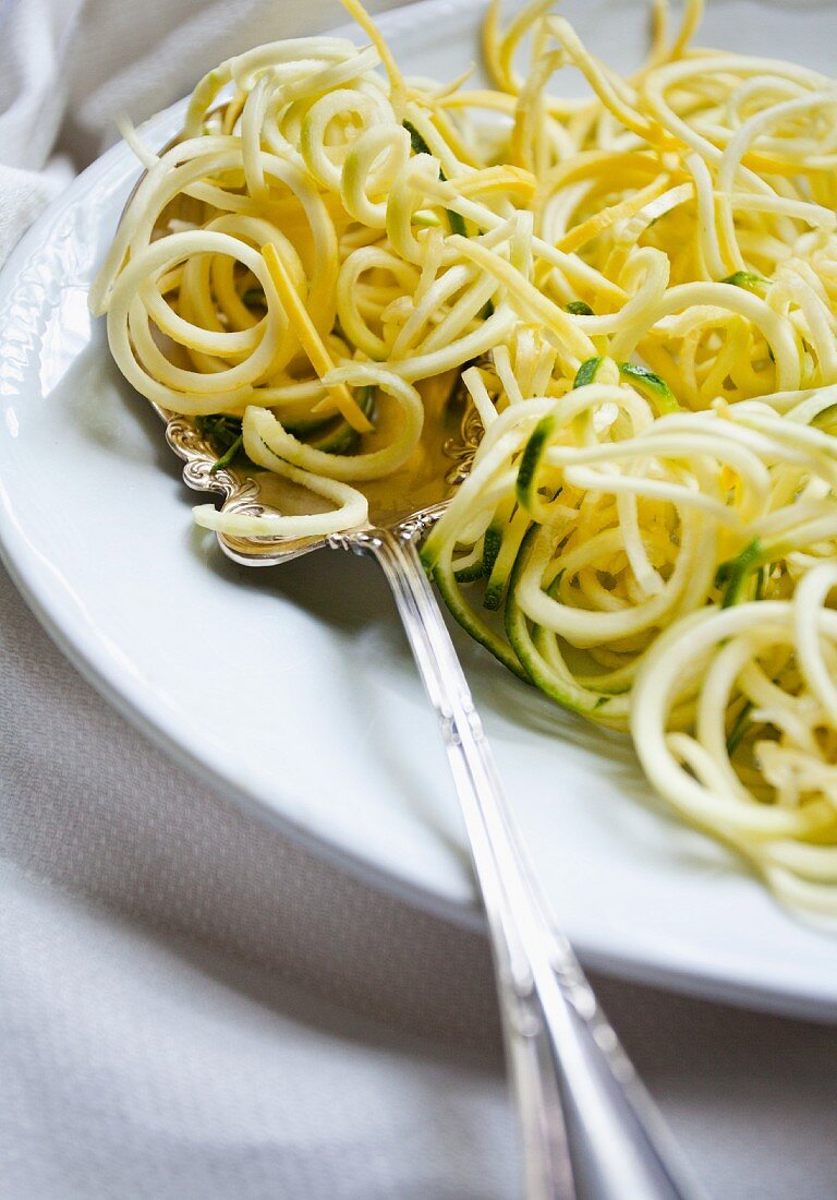 'Spaghetti' aus spiralisierten Zucchini auf Servierplatte