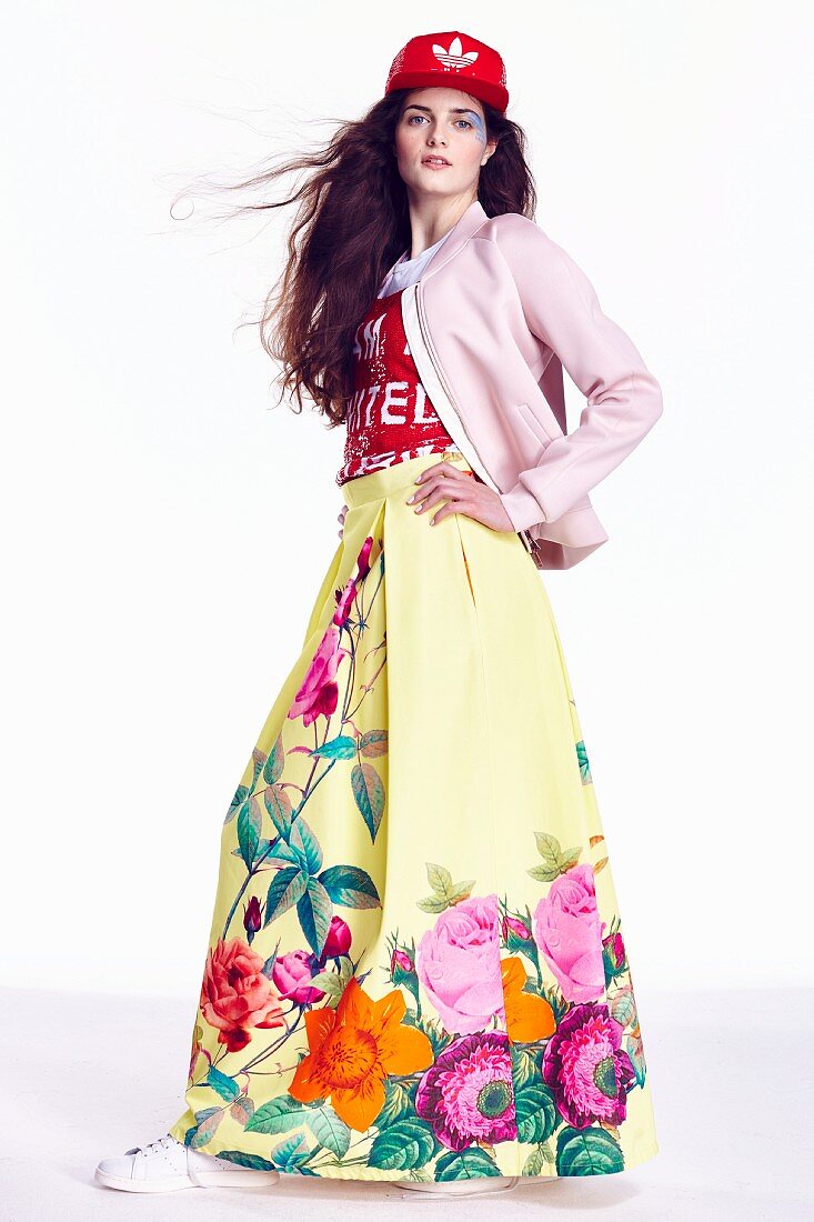 A young woman wearing a colourful outfit with a floral-patterned maxi skirt