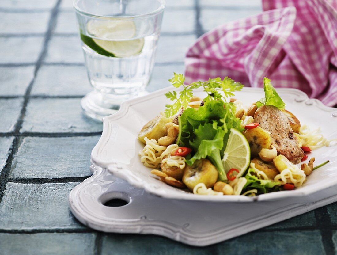 Noodle salad with soya chicken, lettuce, cashew nuts, limes, chilli and fried bananas (Asia)