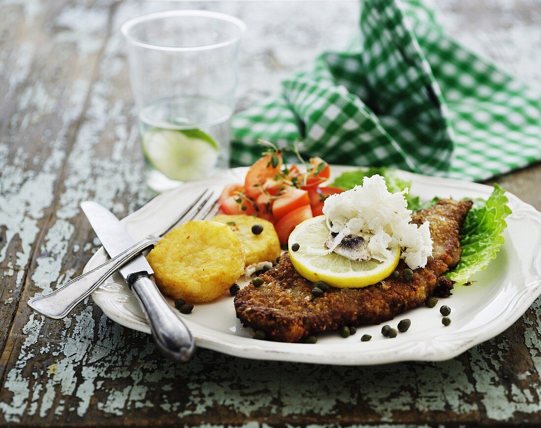 Panierter Fisch mit Kapern, Kartoffeltalern und Tomatensalat