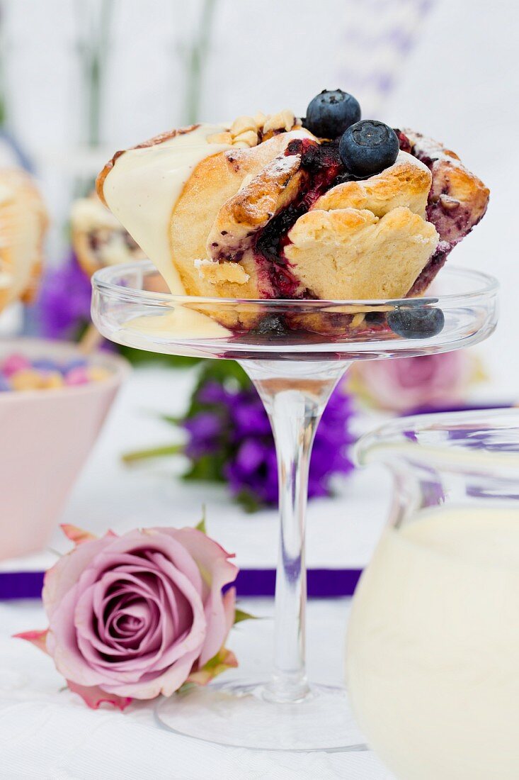 A spiral cake with blueberries and vanilla sauce on a glass stand