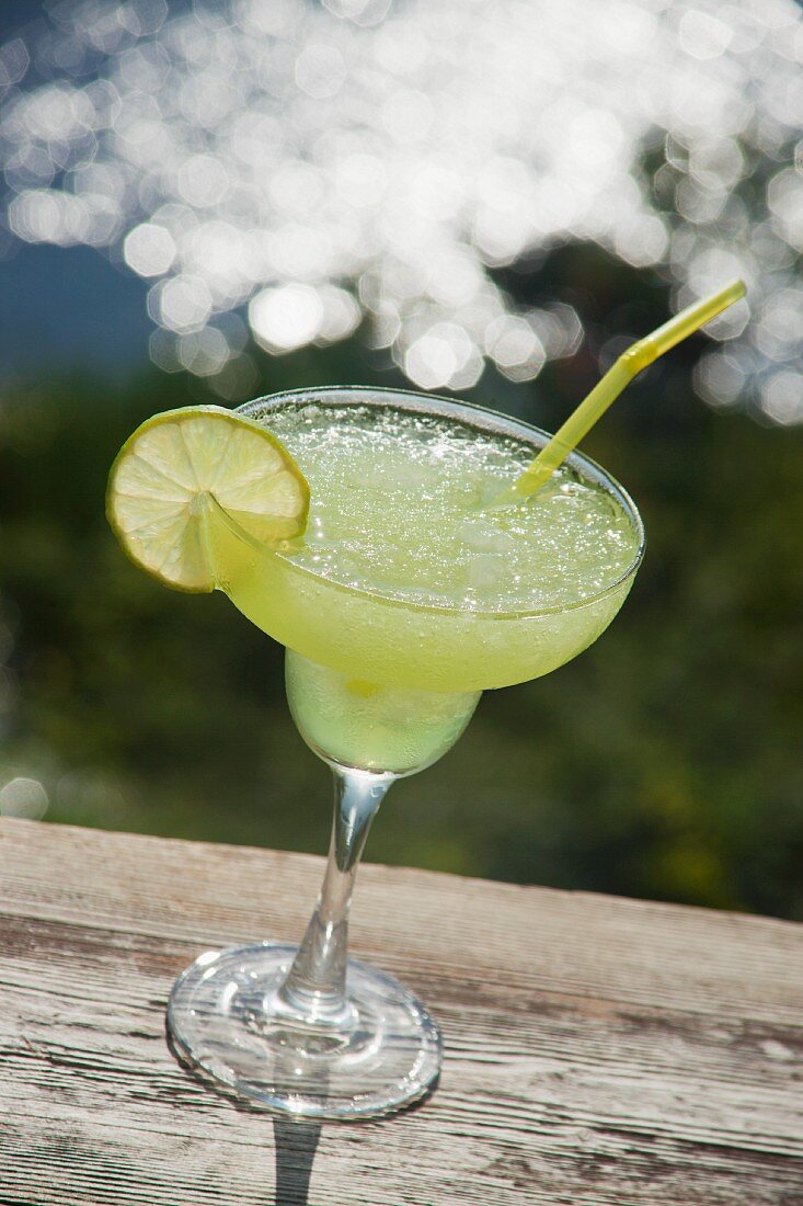 A Margarita cocktail on a wooden table near a lake