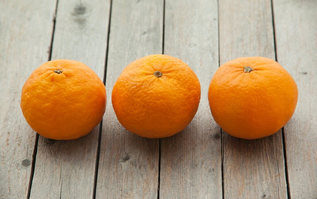 Three mandarins on a wooden surface