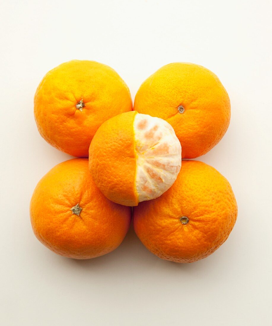 Fünf Mandarinen, eine zur Hälfte geschält