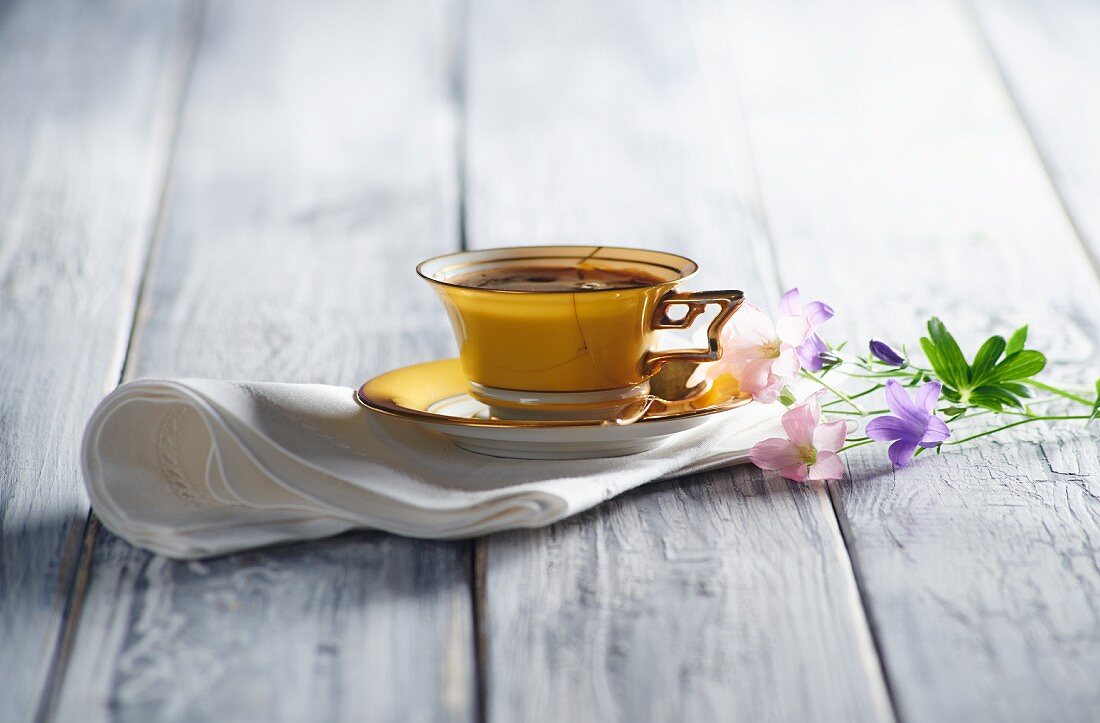 Gelbe Kaffeetasse auf Serviette mit Blumen