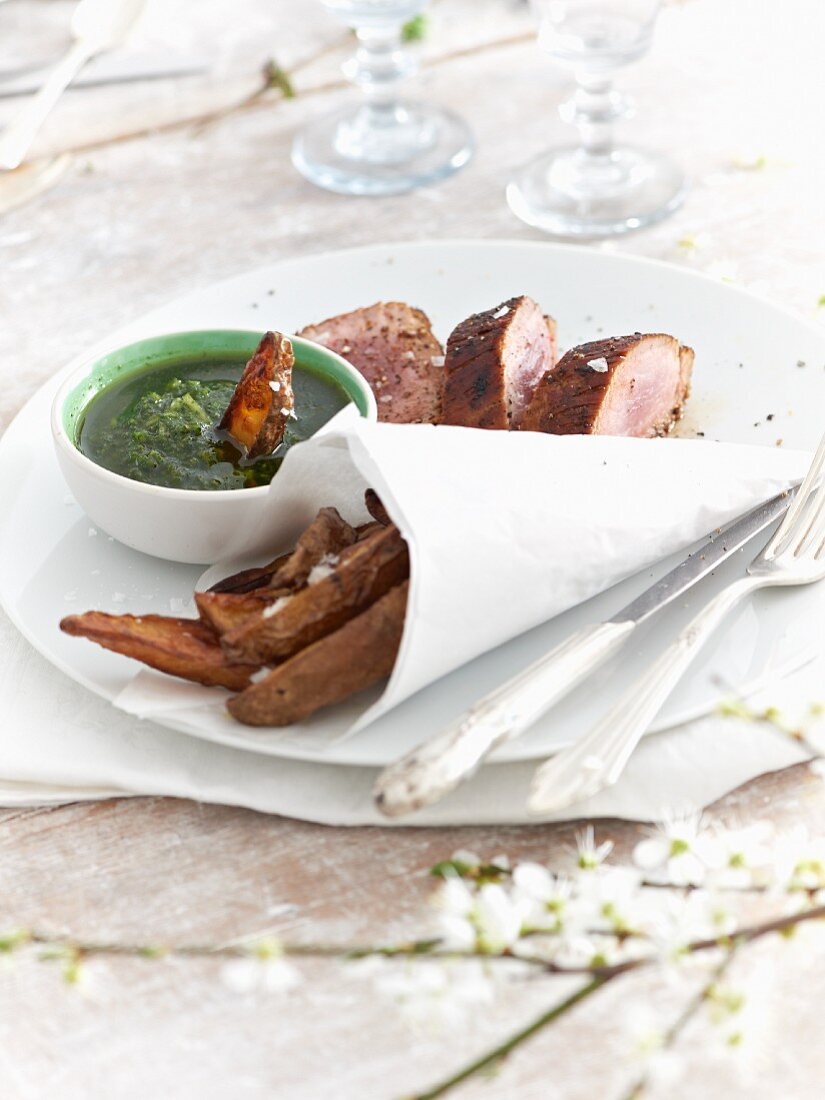Green sauce served with pork fillet and potato wedges