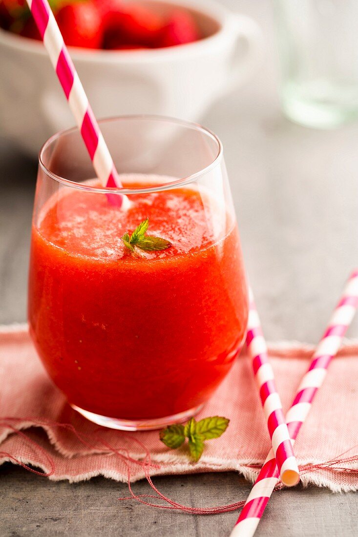 A strawberry and watermelon smoothie in a glass with a straw