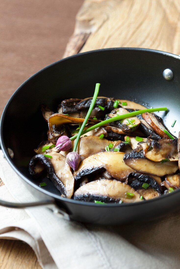 Gebratene Champignons mit Schnittlauch in Pfanne