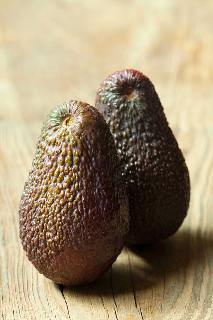 Two avocados on wooden background