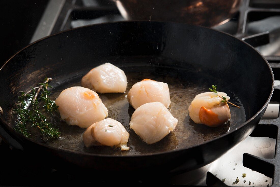 Scallops with thyme in a frying pan