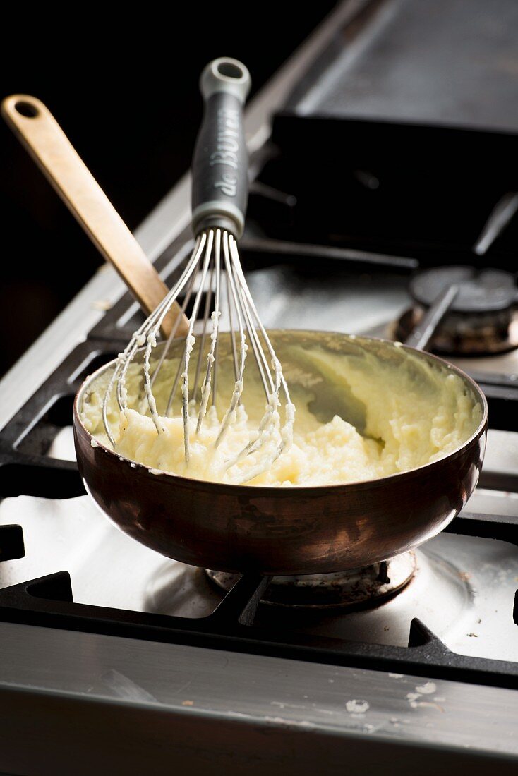 Mashed potatoes in a pan with a whisk