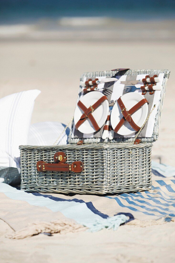 Open picnic basket on beach towel on sandy beach
