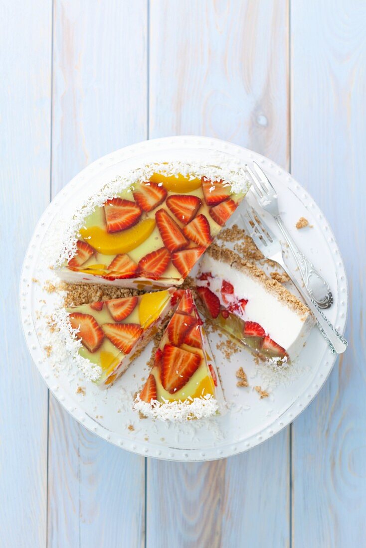 Vanilla yoghurt cheesecake with fruit jelly, strawberries, peaches and coconut