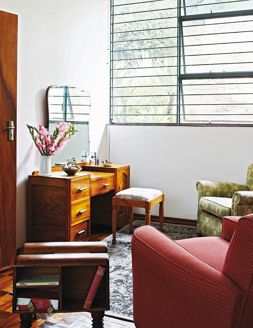 Comfortable armchair and wooden dressing table in corner below open pivot windows