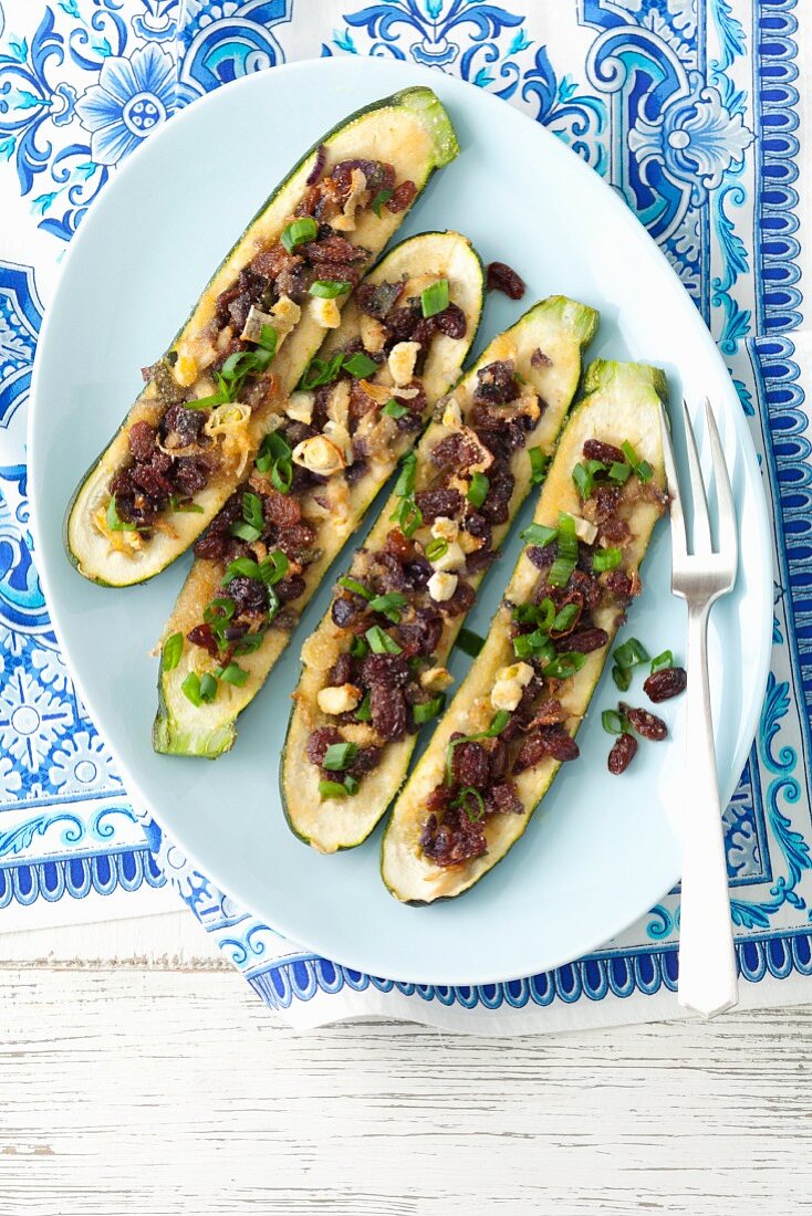 Baked courgettes stuffed with raisins, shallots and red onions