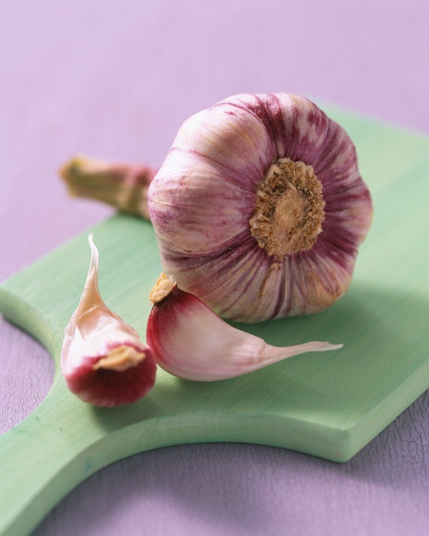 A bulb of garlic and garlic cloves on a chopping board
