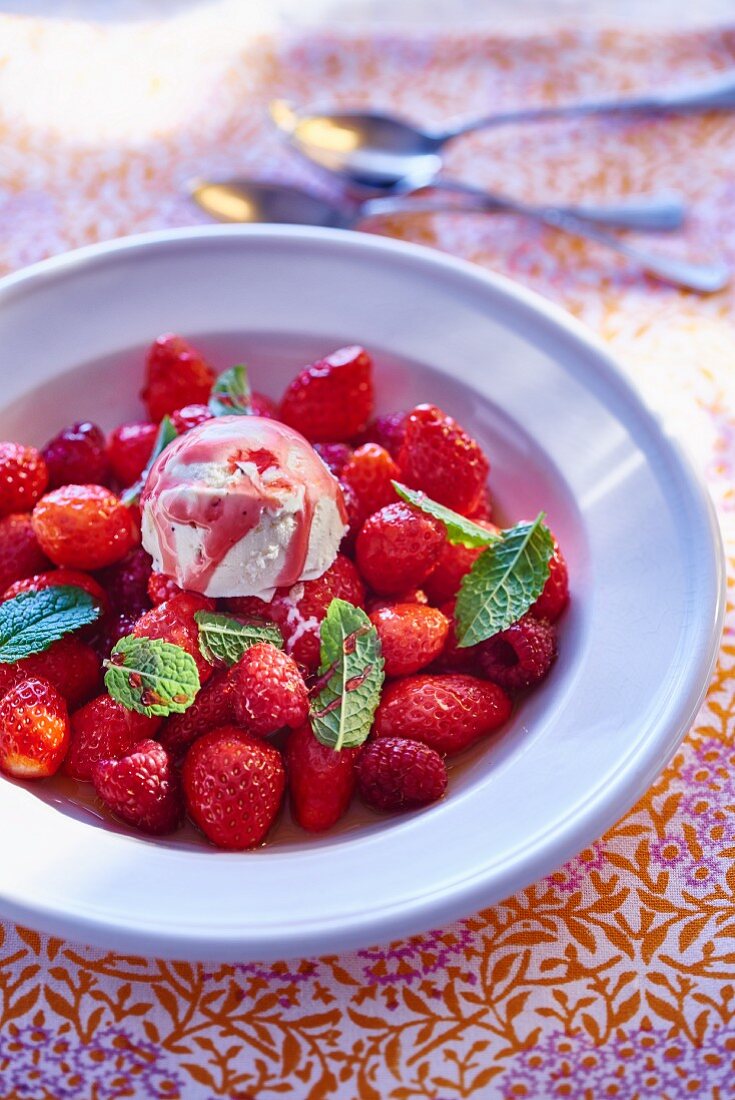 Erdbeer-Himbeer-Salat mit Vanilleeis, Fruchtsauce und Minze
