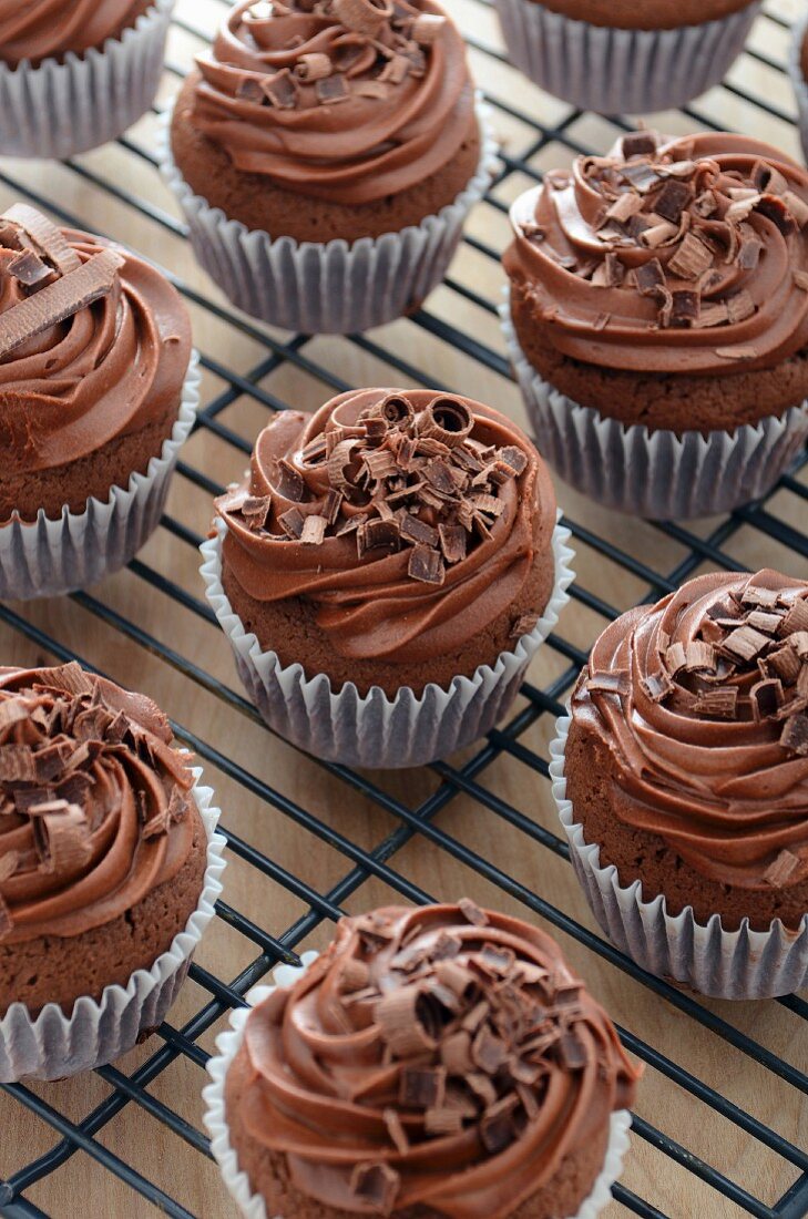 Schokoladencupcakes mit Buttercreme und Schokoraspeln auf Abkühlgitter