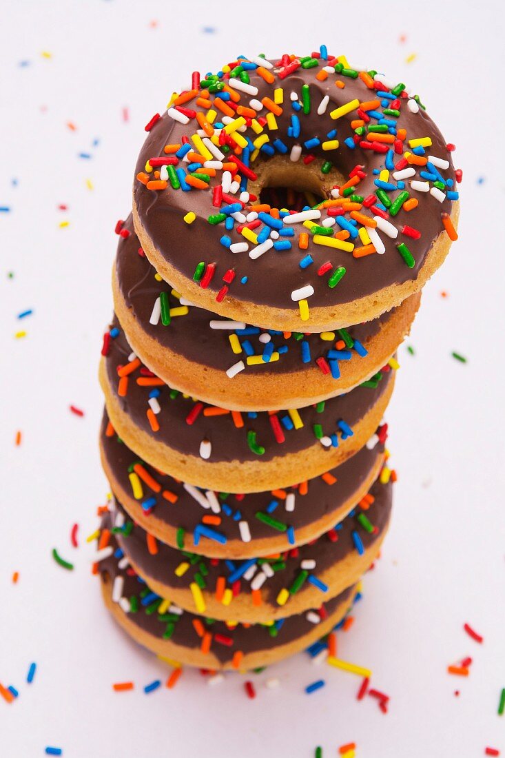 Ein Stapel Doughnuts mit Schokoladenglasur und bunten Zuckerstreuseln