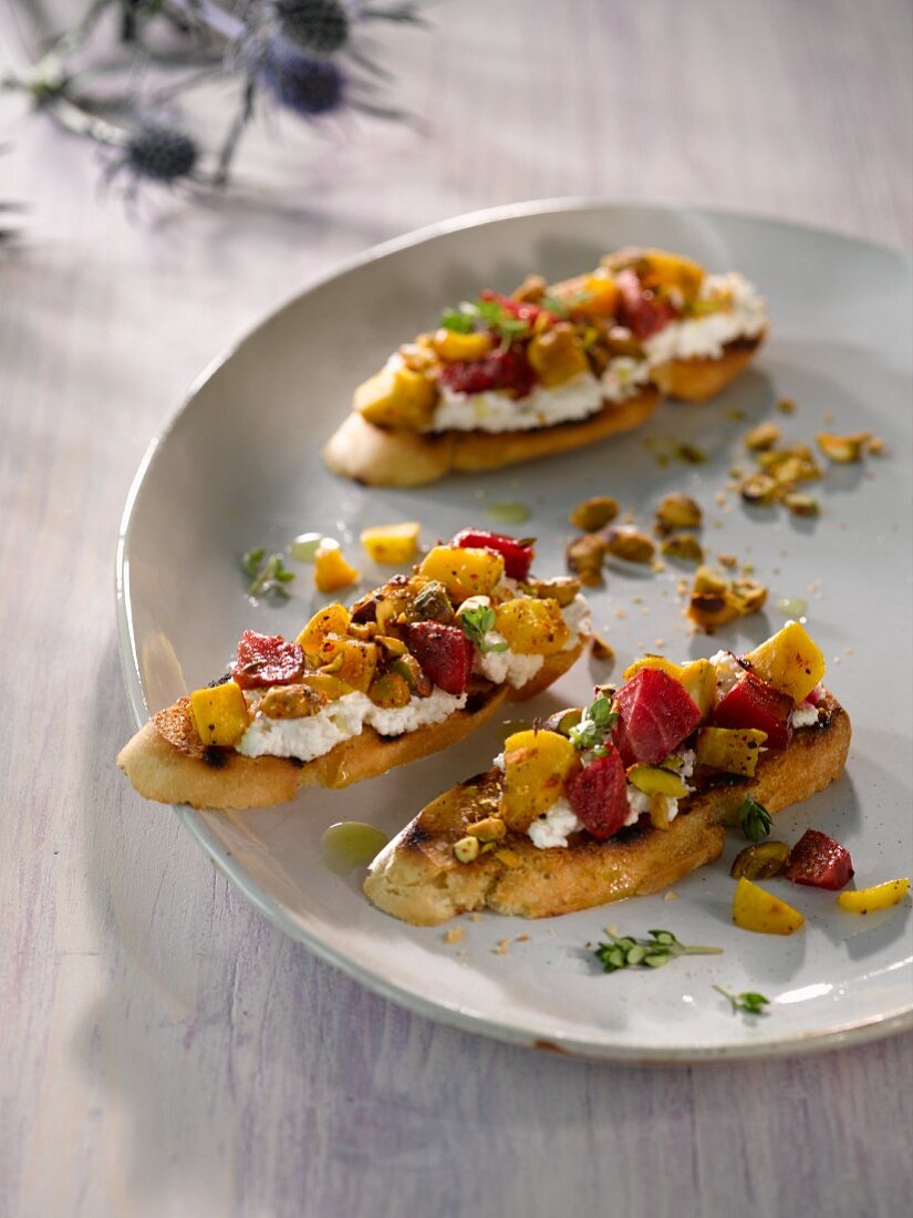 Crostini topped with golden beets and beetroots, cottage cheese and pistachio nuts