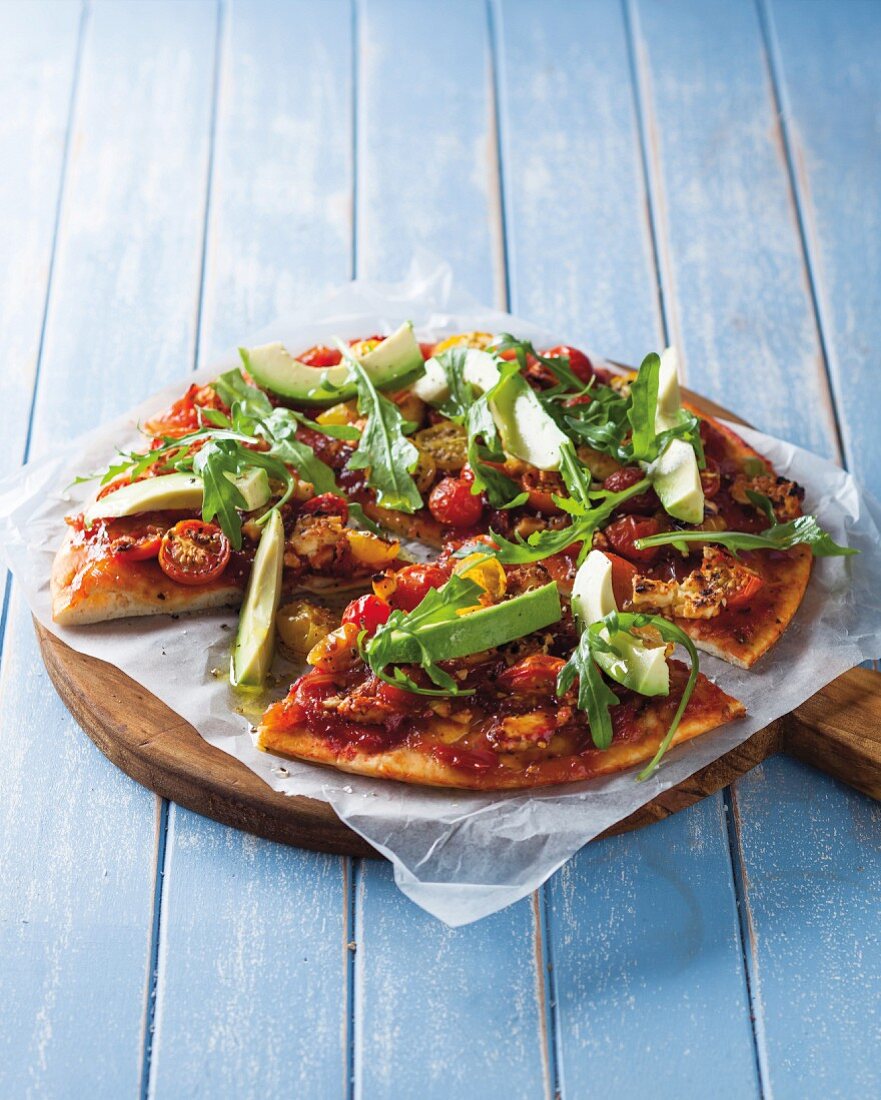 Tomato and avocado pizza topped with rocket