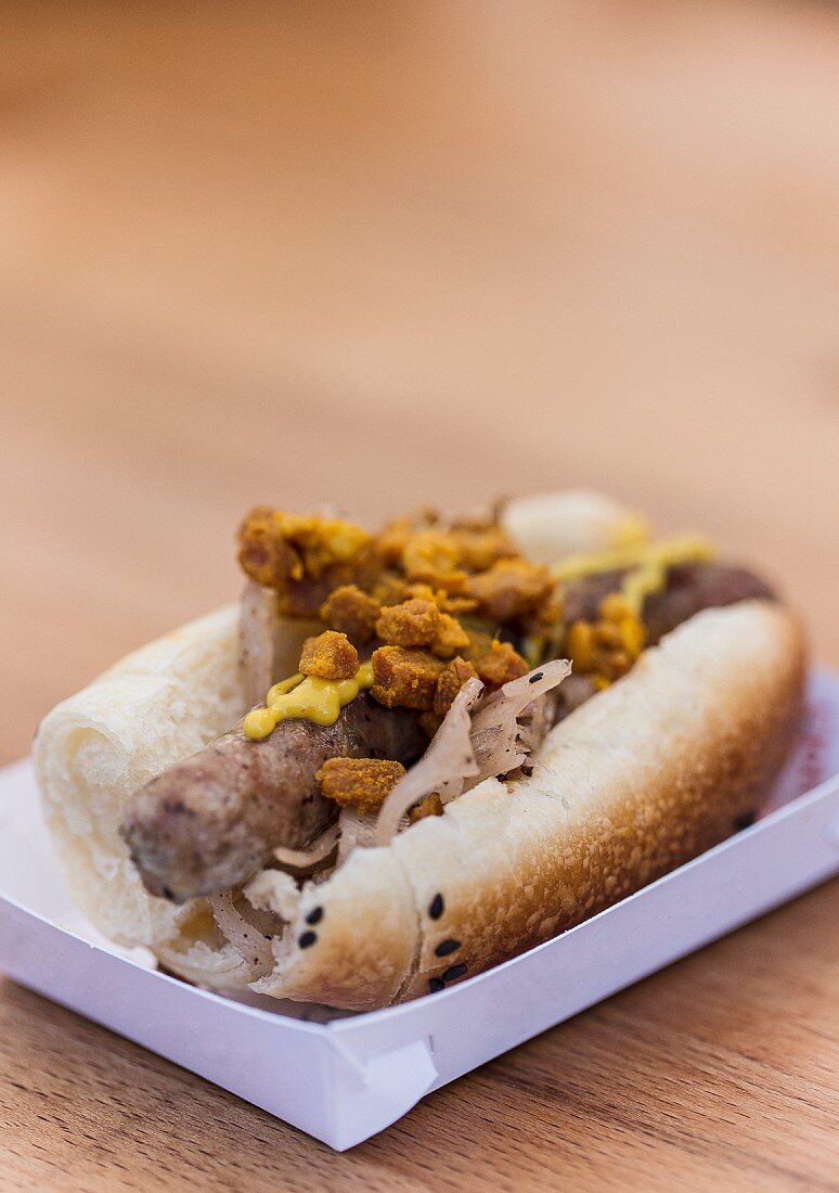Hot Dog mit Bratwurst, Sauerkraut und Grammeln bei einem Imbissstand