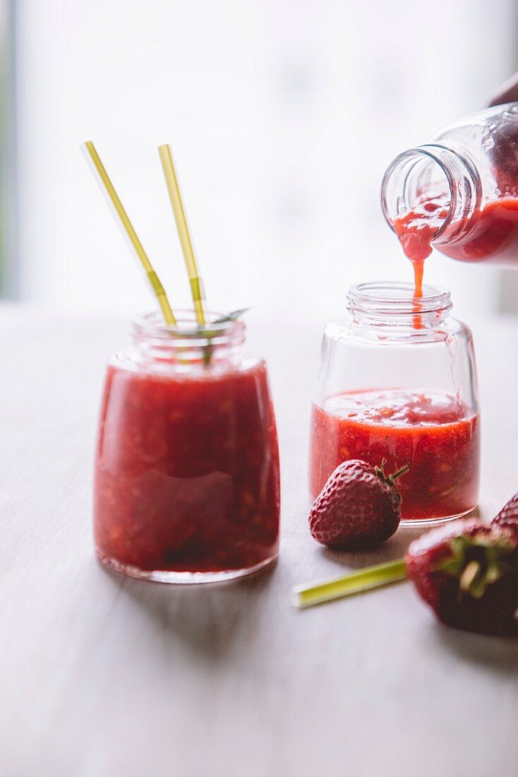 Mango-Erdbeer-Smoothie in Glas einschenken