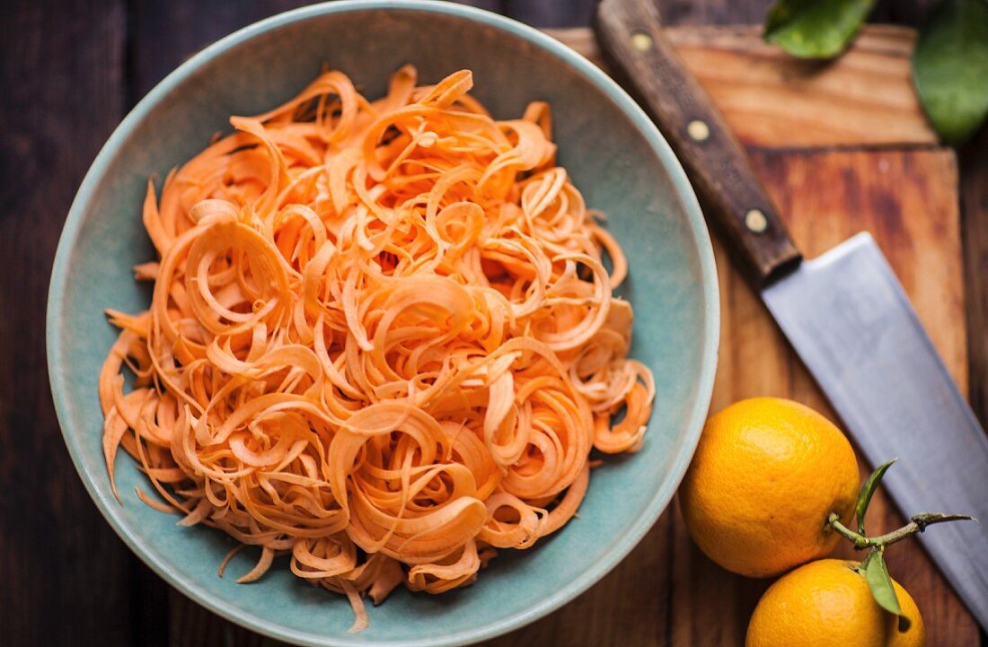 Grated carrots and oranges on a chopping board