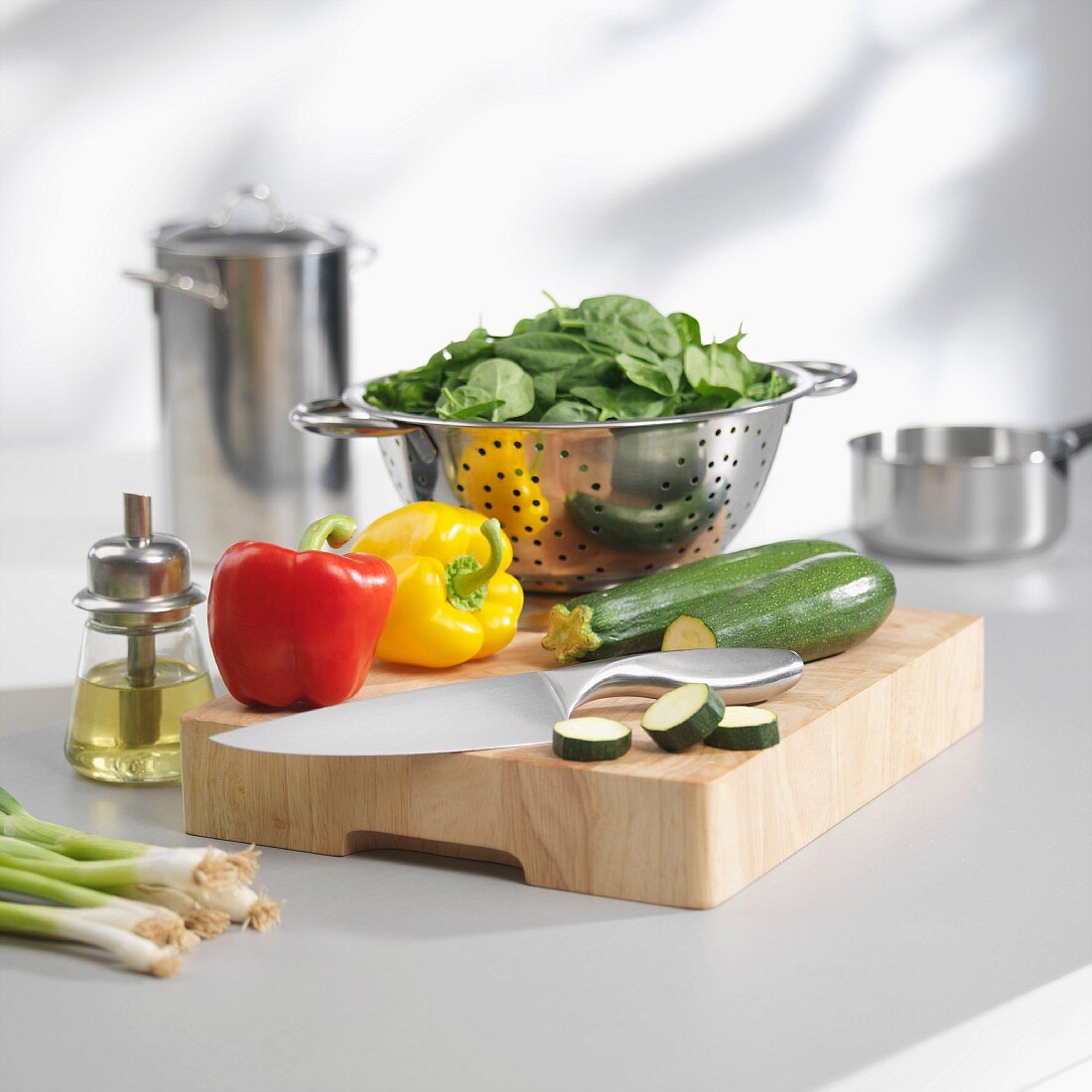 Spinat im Küchensieb und Gemüse auf Schneidebrett