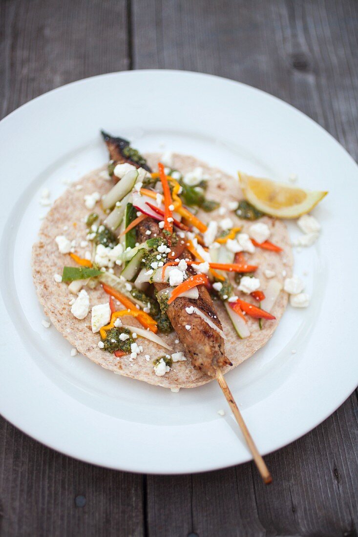 A minced turkey skewer, pickled vegetables and feta cheese on unleavened bread
