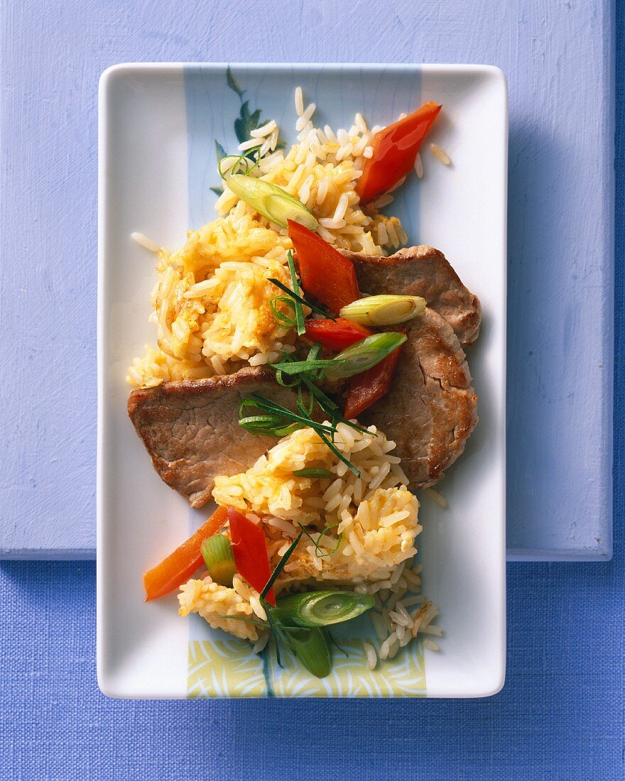 Veal escalope with fried rice, peppers and spring onions