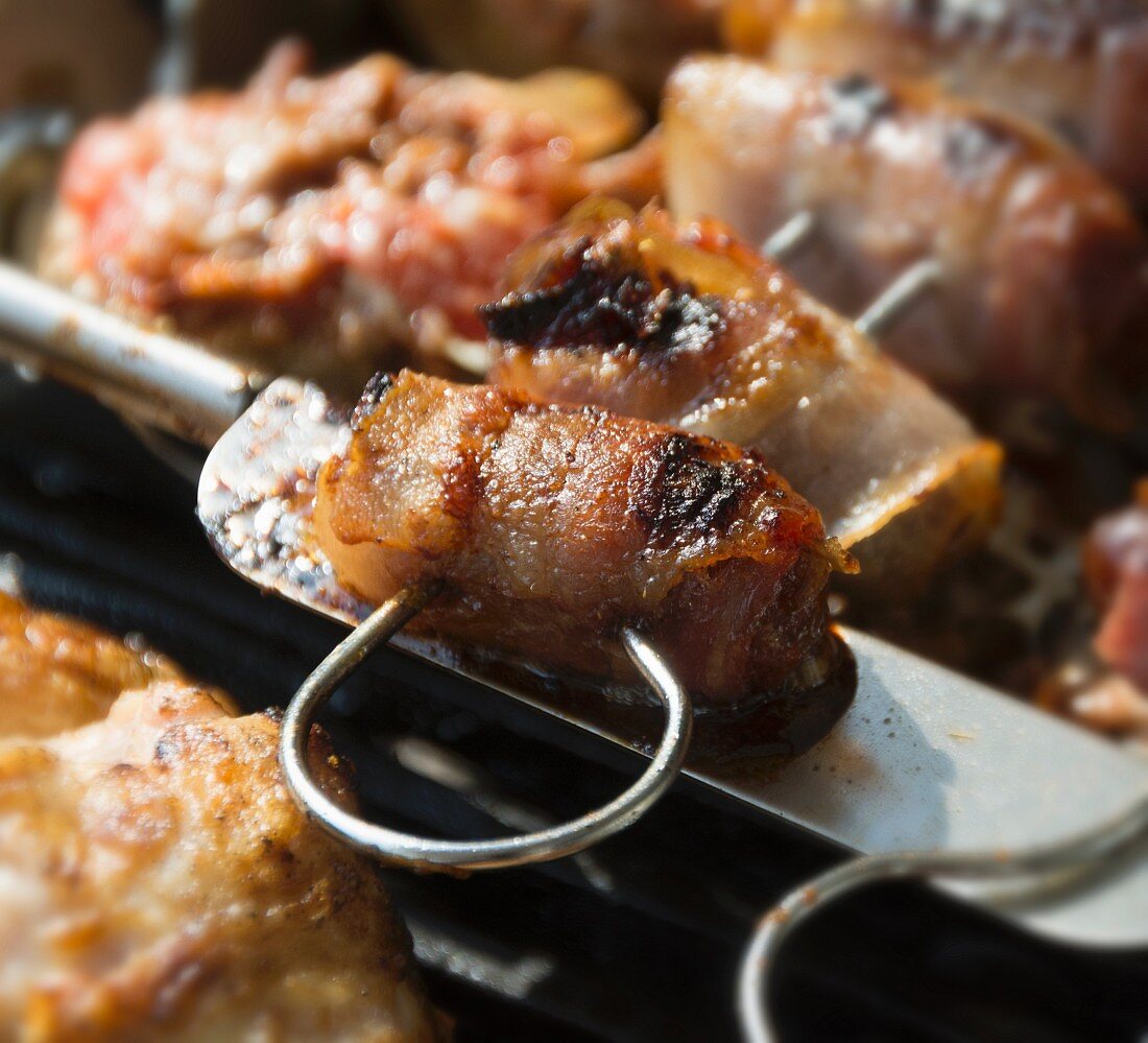 Figs wrapped in bacon on a grill (close-up)