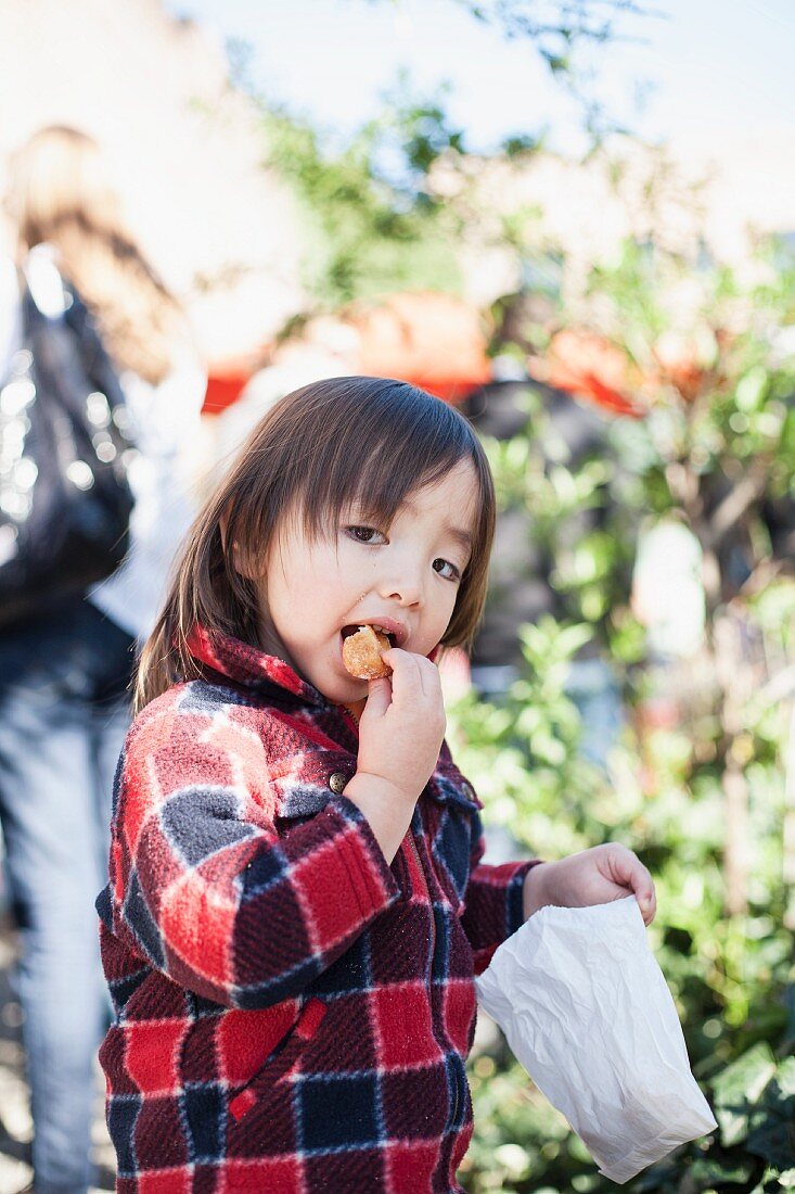 A child eating a snack from a paper bag