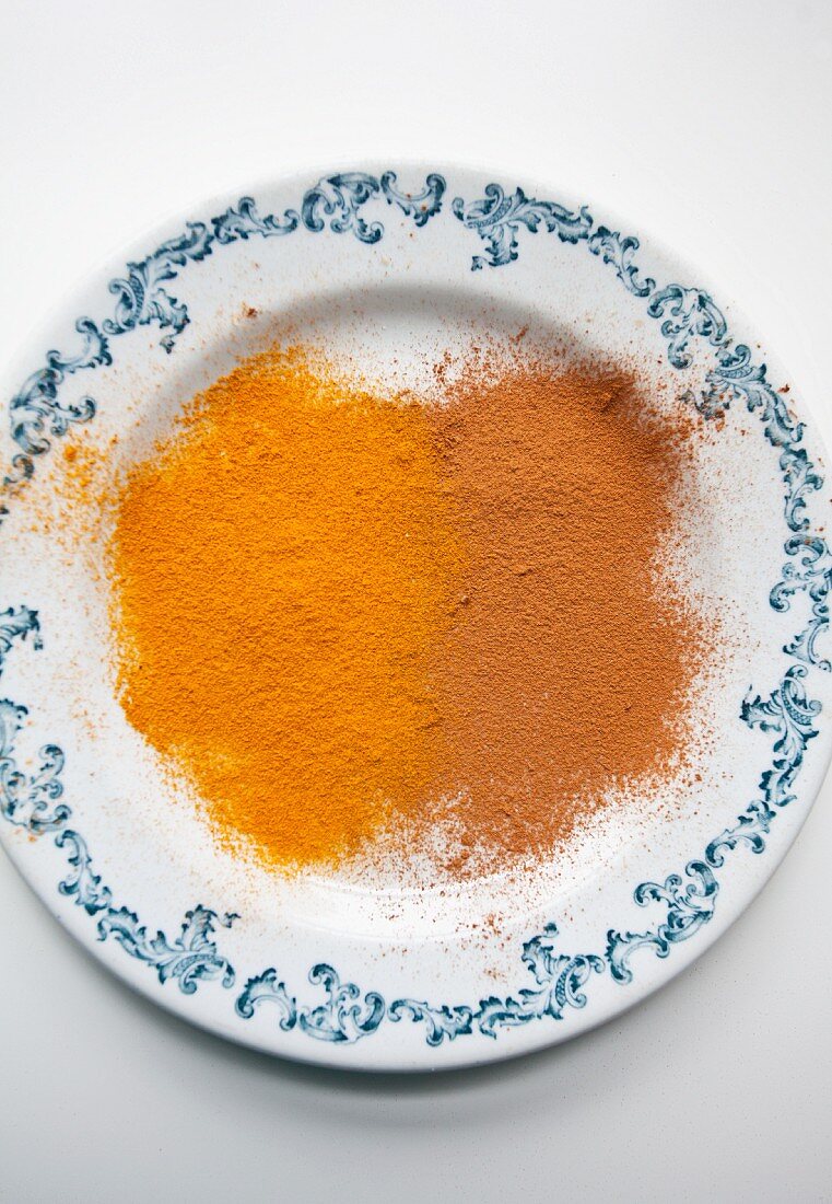 Ground cinnamon and ground turmeric on a blue and white plate