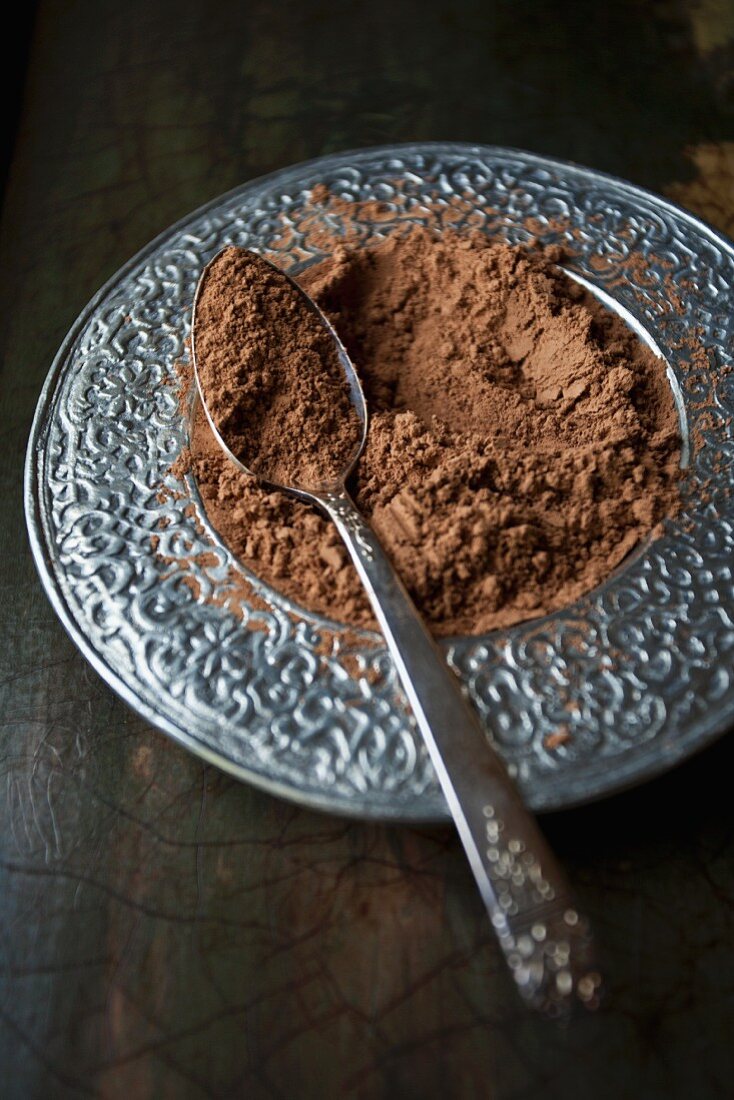 Raw cacao powder in a silver dish with a spoon