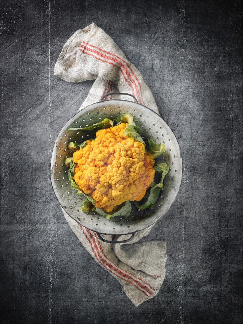 Yellow cauliflower in a colander on a linen cloth
