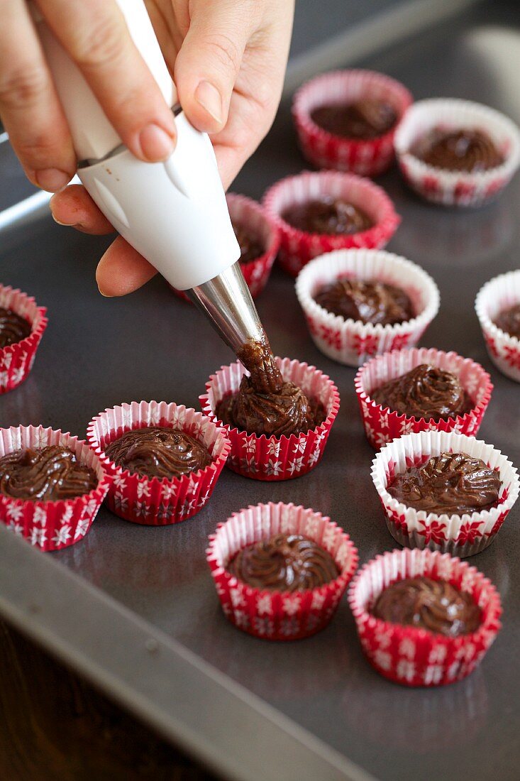 Teigmasse für Mini-Schokoladenmuffins in Förmchen spritzen