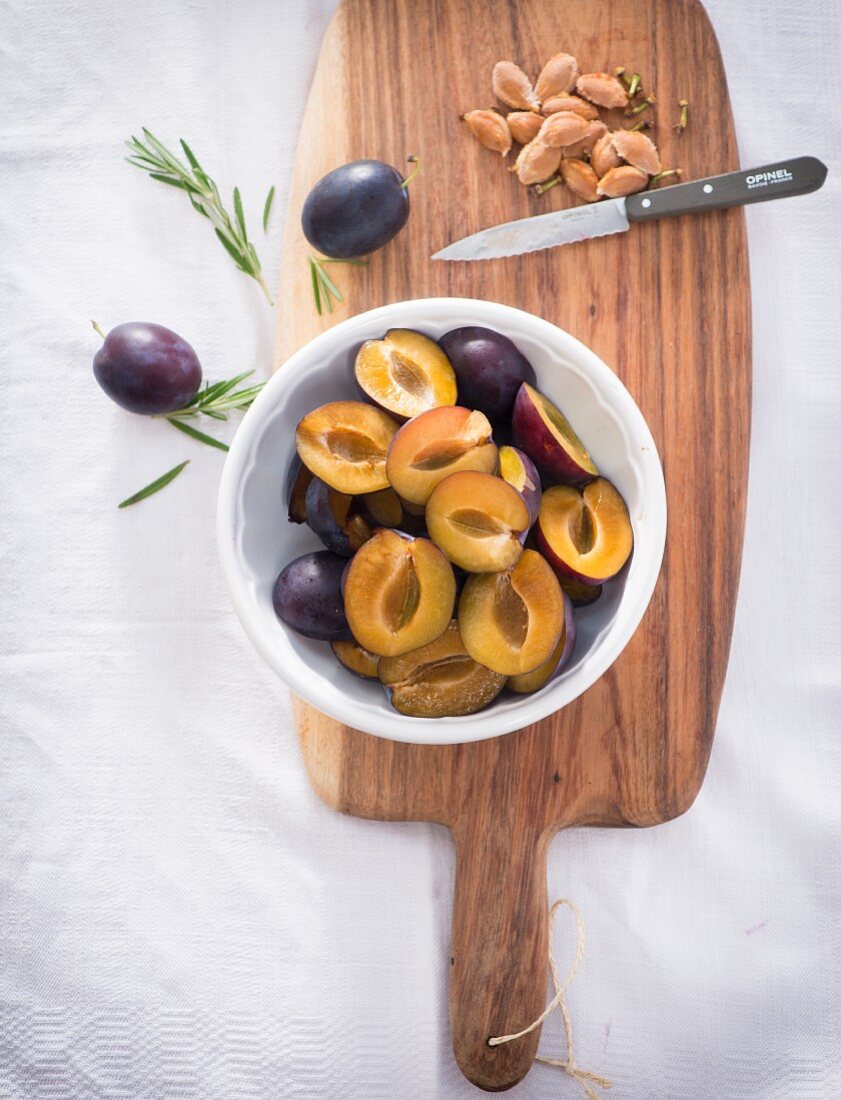 Pitted damsons in a bowl on a wooden board
