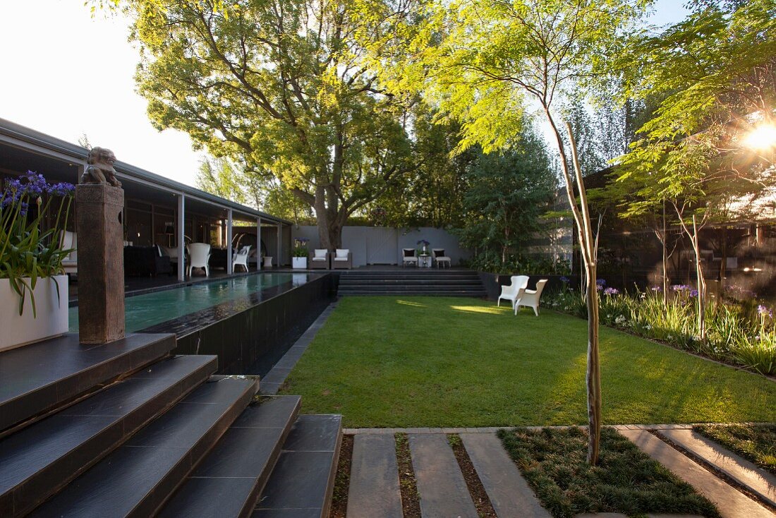 Rasenfläche und Treppe zur Terrasse mit vorgelagertem Pool