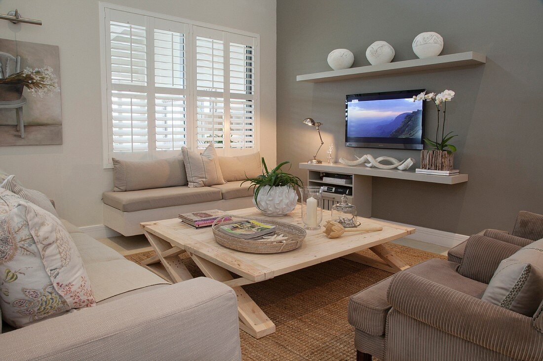 Sitzbereich vor dem Fernseher mit skandinavischem Naturholztisch und gepolsterter Sitzbank unter dem Fenster