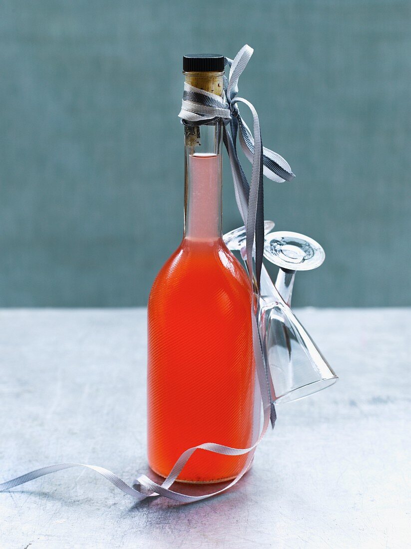 A bottle of homemade orange liqueur as it gift with glasses