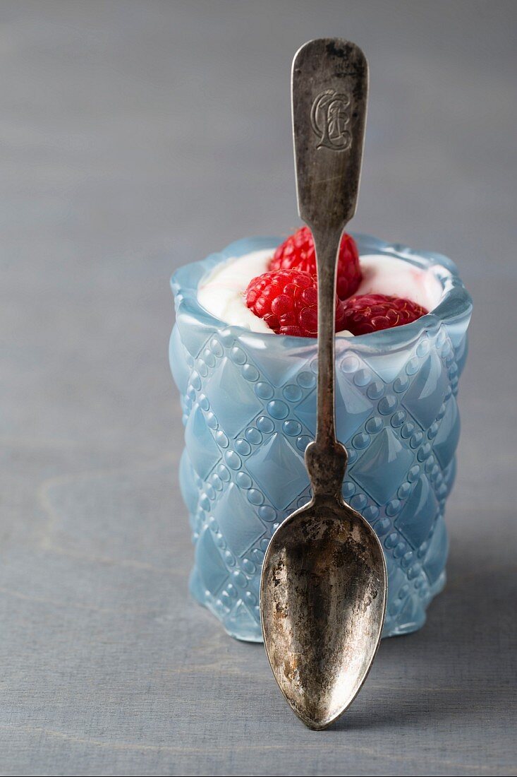 Yoghurt with raspberries in a glass with a spoon