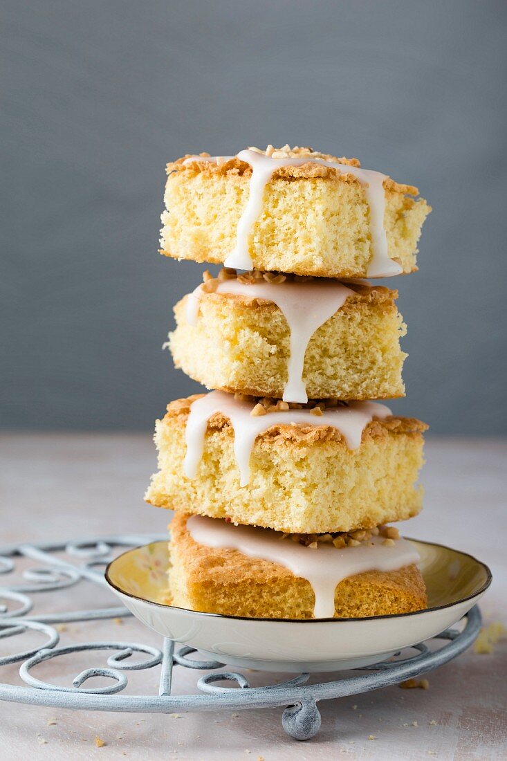 A stack of vanilla cake slices with icing and hazelnuts