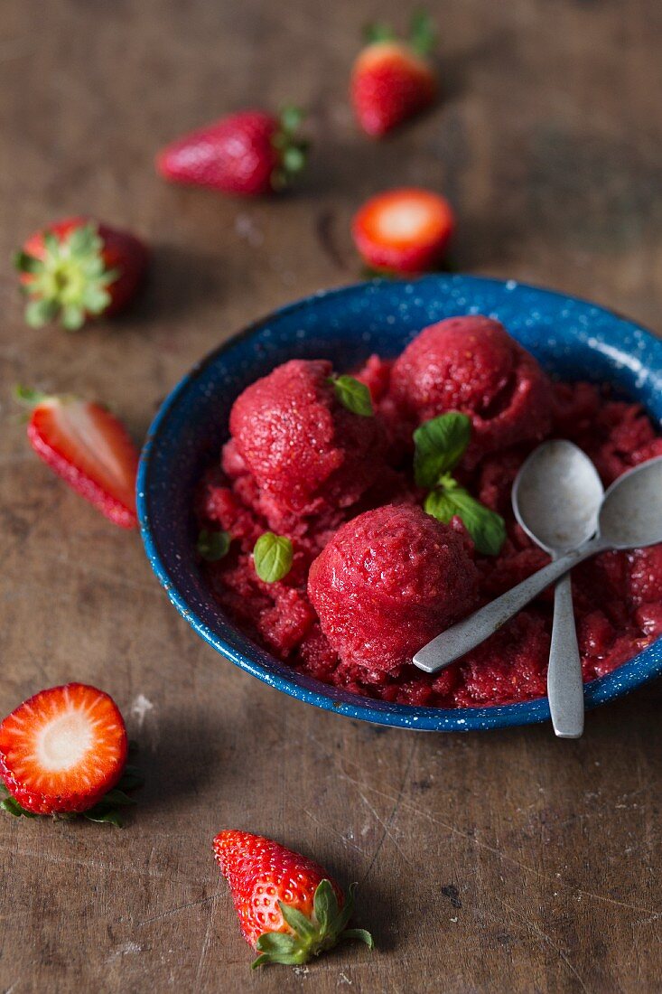 Strawberry sorbet with fresh mint in a rustic blue bowl