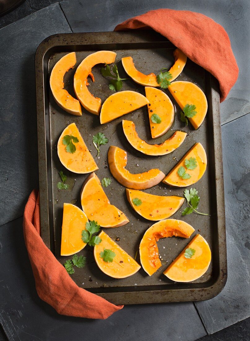 Butternut squash wedges with coriander on a baking tray ready for roasting