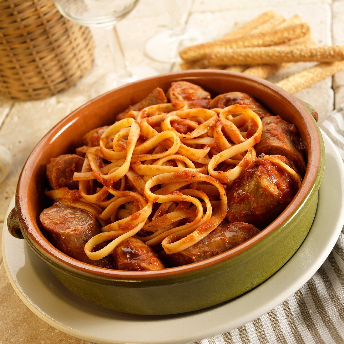 Fettuccine with sausage with marinara sauce in a ceramic bowl
